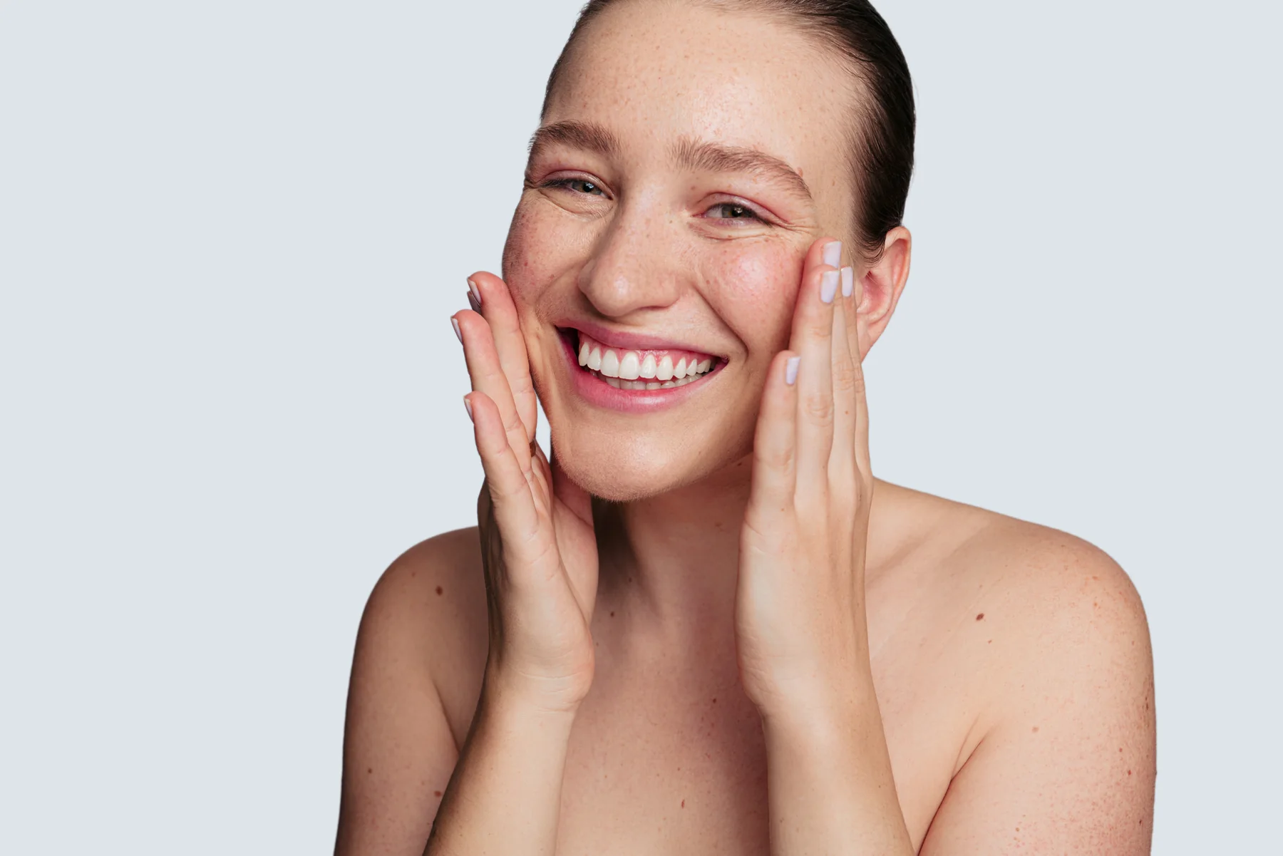 Woman smiling and touching her rejuvenated face after a Salt Facial.